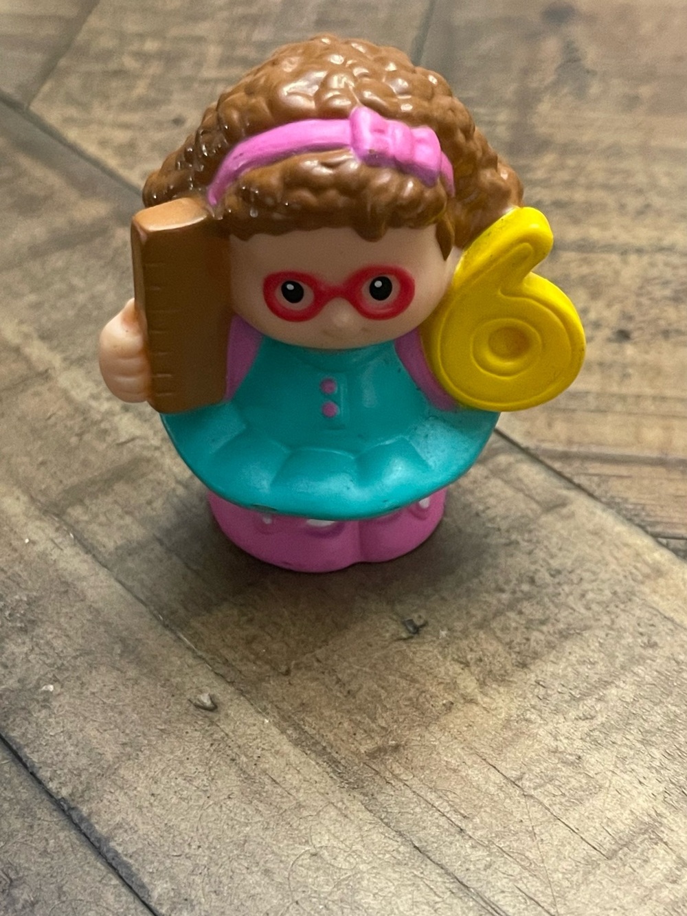 Little People Maggie figure holding a yellow number six from the Time to Learn